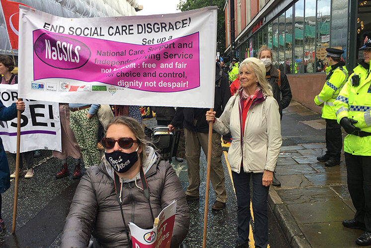 People outside with banner stating End Social Care Disgrace.