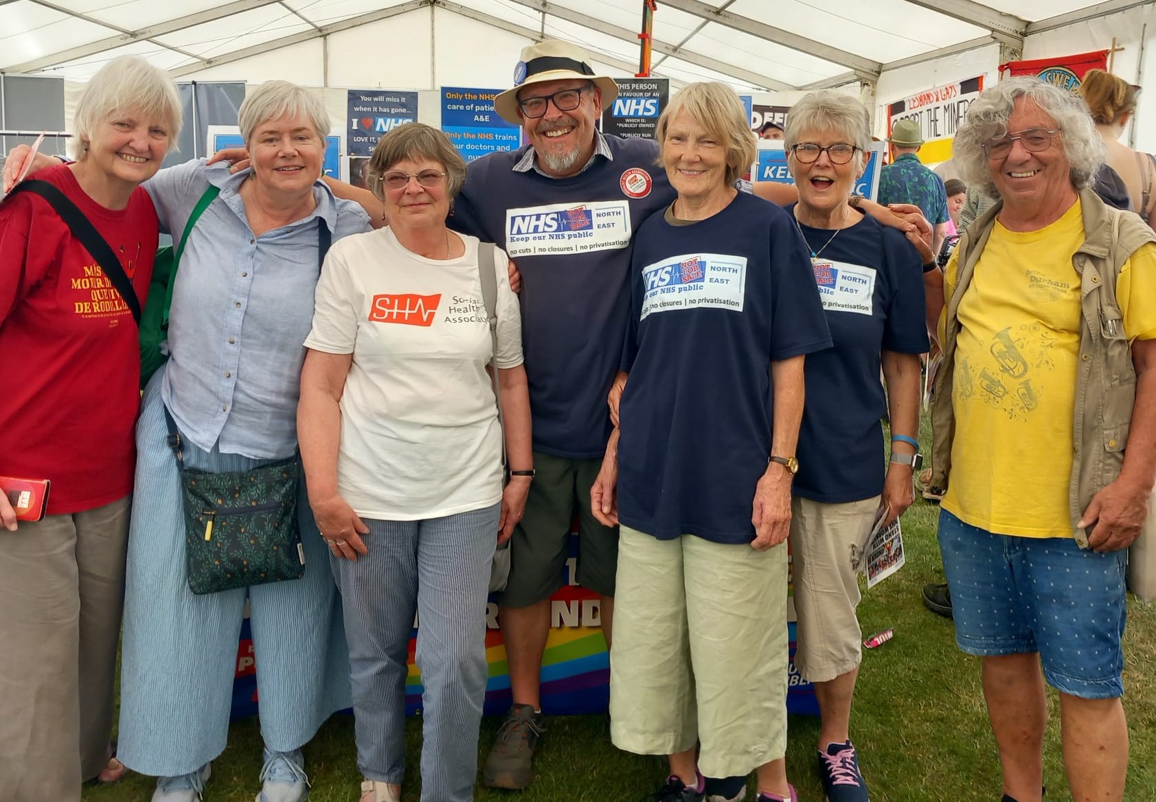 Seven people pose for a photo wearing Keep Our NHS Public T-Shirts
