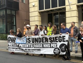 A large group of people hold a Unite the union banner in support of the NHS
